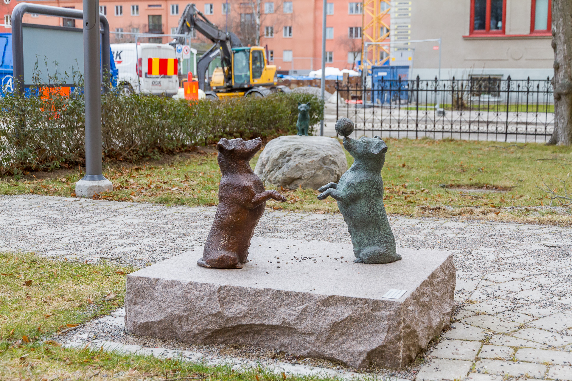 Två hundar i brons med en katt i brons i bakgrunden.