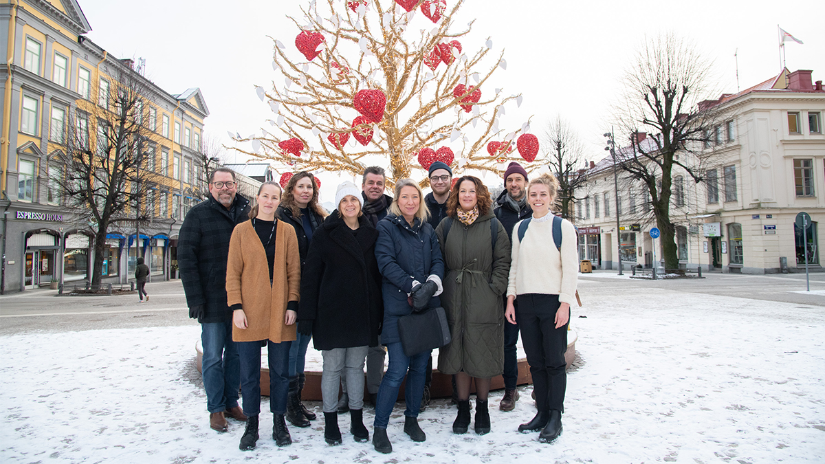 Tio personer som står på Stortorget i Örebro framför vinterdekorationen "kärlekens träd".
