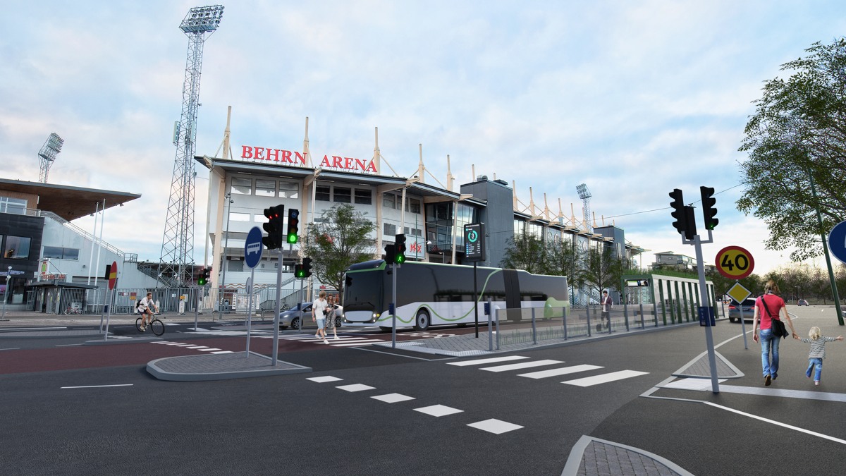 Korsning vid Behrn Arena med övergångsställe, en mittförlagd busshållplats och en passerande buss.