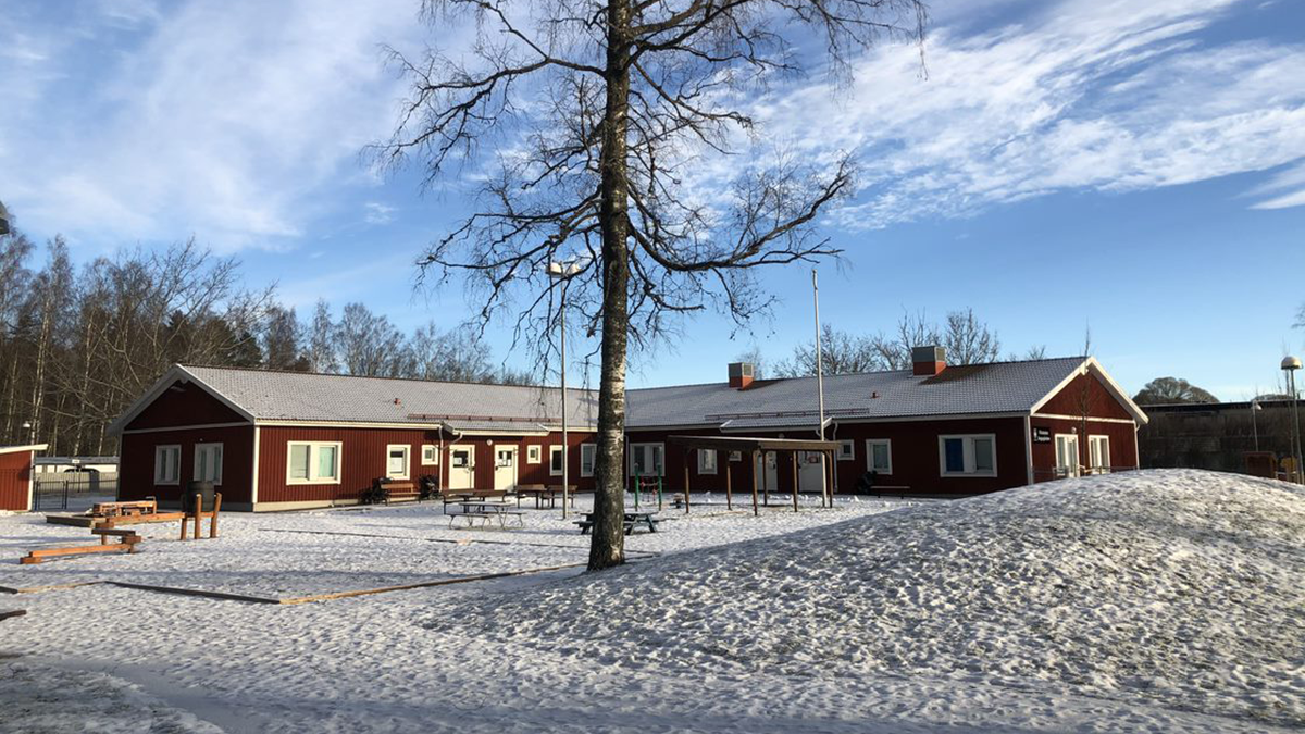 Sagogårdens förskola - rött hus med lekpark framför och snötäckt mark.
