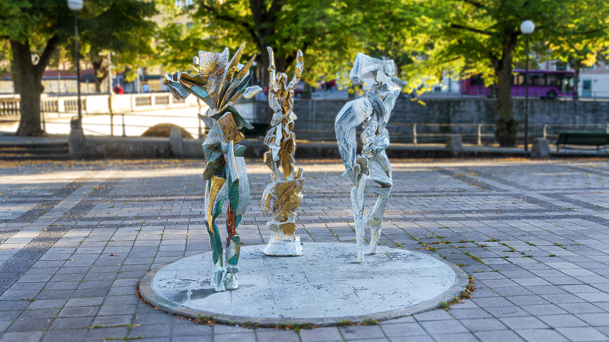 Three abstract figures reminiscent of dancing people. The colors are white and gold.