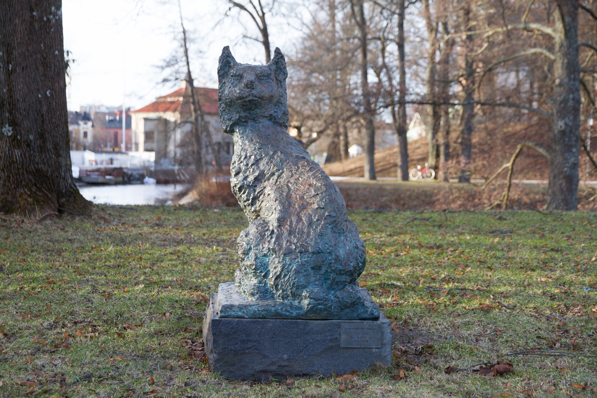 A lynx sitting on a rock. The statue is in bluish bronze.