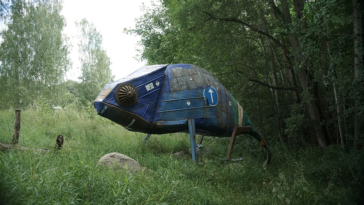 A bright blue giant chameleon with a light green tail made of old picture parts and scrap steel.