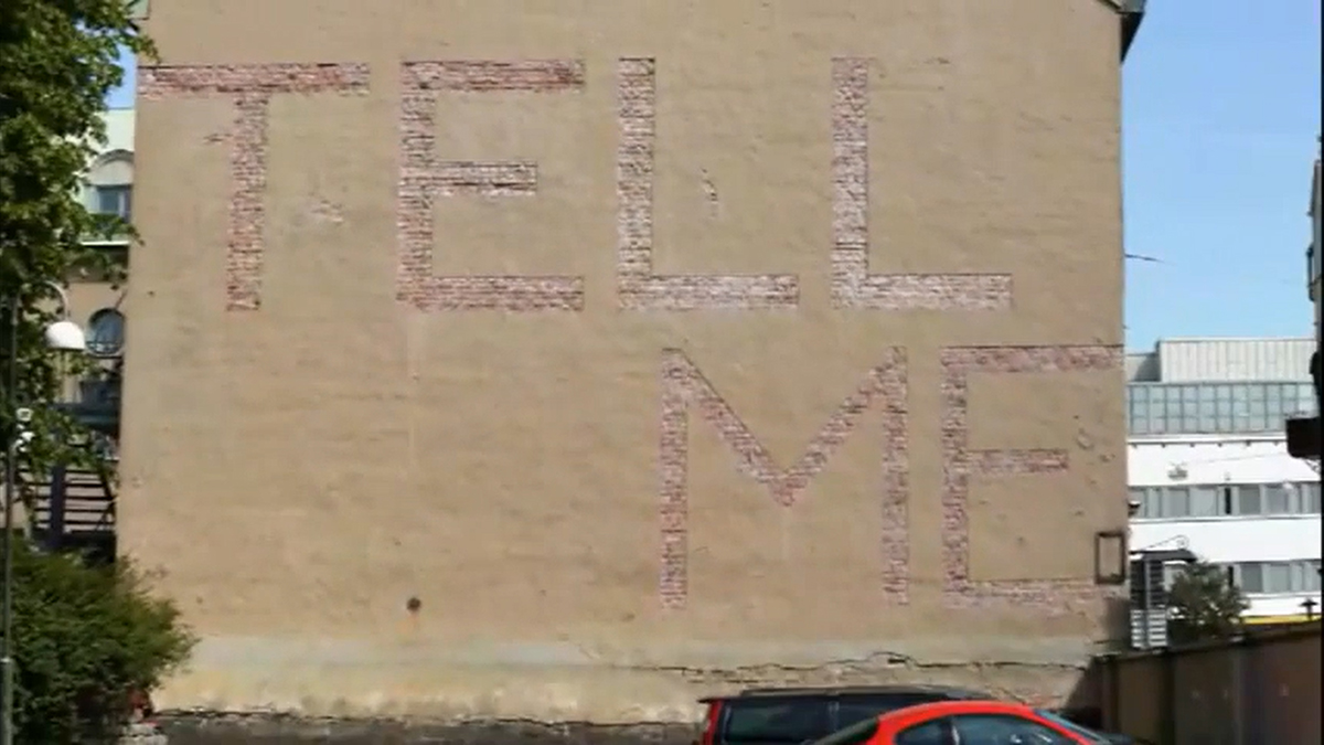 Wall where plaster has been partially taken so that the words "Tell me" were created.